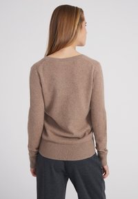 Brauner gestrickter Pullover mit lässiger Passform, gerippten Bündchen und Saum, weicher Textur und weitem Ausschnitt, von hinten betrachtet.