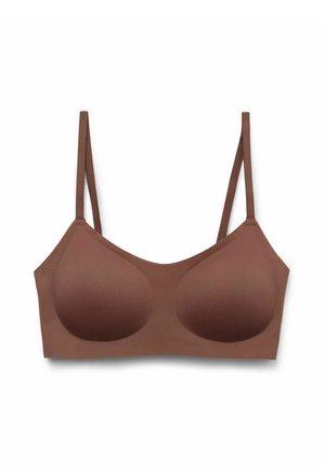 Brązowy bezszwowy biustonosz bez fiszbin z formowanymi miseczkami i cienkimi, regulowanymi ramiączkami na białym tle.