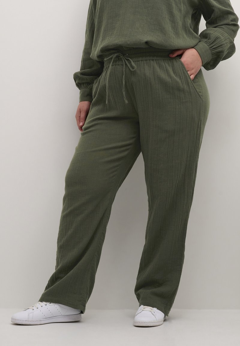 Olivgrüne, leichte Stoffe, weit geschnittene Hosen mit strukturierter Oberfläche. Mit einem elastischen Bund und Kordelzug sowie seitlichen Taschen.