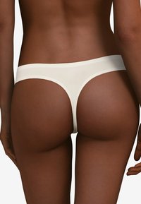 Witte string ondergoed met een gladde, rekbare stof en een tailleband met een lage taille, met een minimalistisch ontwerp en naadloze constructie.