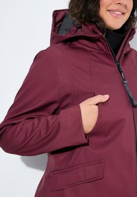 Chaqueta impermeable burdeos con capucha, que cuenta con cierre de cremallera, bolsillos laterales y un forro interior texturizado para mayor comodidad y protección.