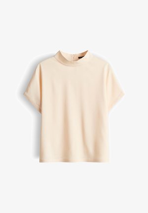 Blusa beige a maniche corte con collo alto e cerniera posteriore, esposta su sfondo bianco.