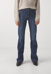 Mörkblå denimjeans med rak bendesign, som har fem fickor, subtila stickdetaljer och en klassisk knappstängning vid midjan.