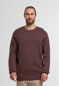 Bordeauxfarbener Rippenstrickpullover mit langen Ärmeln, Rundhalsausschnitt und geradem Schnitt. Weiche Textur mit leicht lockerer Silhouette.