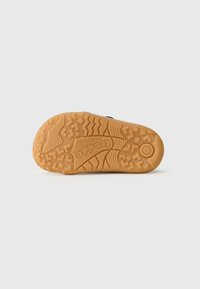 Rubberen sneakerzool in tan kleur met een gestructureerd profiel. Voorzien van een opvallend logo en verschillende gripontwerpen voor optimal grip.