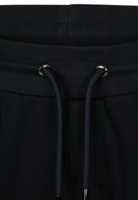 Zwarte sportshorts met een geribbelde tailleband, voorzien van een koord met metalen aglets. Het materiaal lijkt glad en rekbaar.