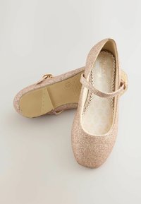 Zapatos Mary Jane rosas con purpurina, punta redonda, correa ajustable y suela de goma texturizada. El interior presenta un patrón de hojas.