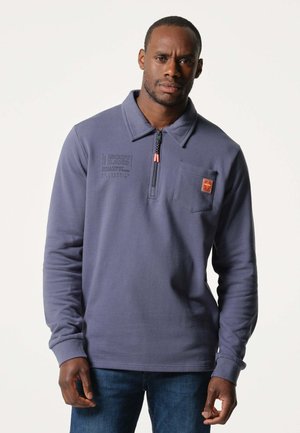 Pullover in donkergrijze fleece met een ritskraag, voorzien van een borstzak en oranje logo. Soepele textuur en gestructureerde branding.