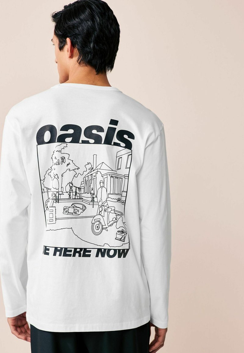 Ilgų baltų rankovių marškiniai su juodu kontūruojančiu miesto peizažo piešiniu ant nugaros, su tekstu "oasis" ir "BE HERE NOW" ryškiais šriftais.