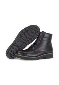 Botas de cuero negro hasta el tobillo con punta redonda, seis ojetes, suela de goma con tracción y detalle de costura en contraste alrededor de la suela.