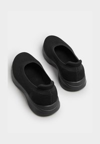 Schwarze Slipper mit einem Mesh-Obermaterial, runder Zehenpartie und einer dicken Gummisohle. Texturiertes Design und eine gepolsterte Ferse für zusätzlichen Komfort.