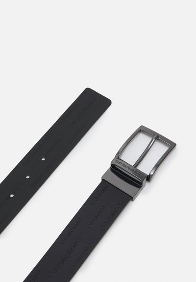 Czarny gumowy pasek z wytłoczonym logo "Emporio Armani", wyposażony w prostokątną, srebrną metalową klamrę i wieloma otworami do regulacji.