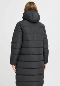 Melnā pūšamā jaka ar kapuci, ar quilted dizainu, garām piedurknēm un vidēja garuma griezumu, izgatavota no gludas, ūdensizturīgas materiāla.