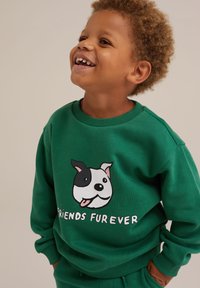Zelená mikina vyrobená z bavlny, so vzorom psa a textom "FRIENDS FUREVER" v bielej farbe. Hladký golier a manžety.