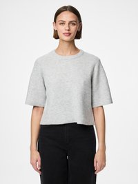 Helehall, soonikkoesega lühikeste varrukatega kampsun ümarate kaelustega, lühendatud lõikega ja pehme tekstuuriga, koos mustade laiade säärega pükstega.