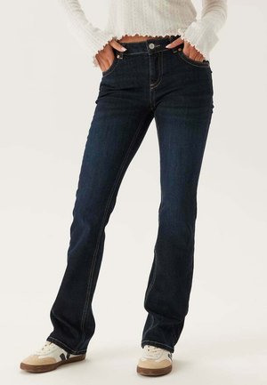 Mörkblå utsvängda jeans i denim, med hög midja, kopparfärgad sömnad och klassisk femficksdesign.