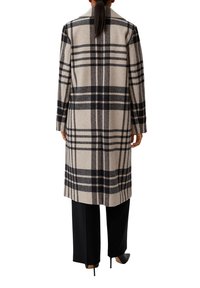 Langer karierter Mantel in Beige mit Schwarz- und Grautönen, mit tailliertem Schnitt, langen Ärmeln und breitem Kragen. Kombiniert mit schwarzen Hosen.