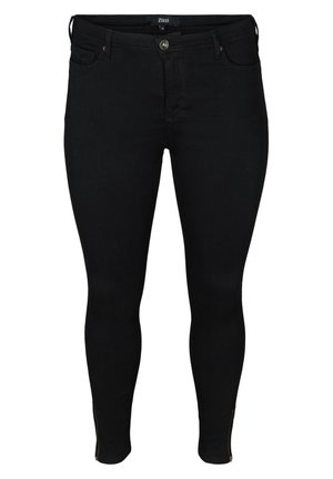 Jean slim noir avec une texture lisse, dotés d'une fermeture à bouton à l'avant et de fermetures éclair aux chevilles pour un détail supplémentaire.
