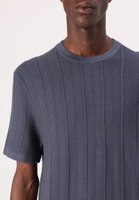 Koszulka z krótkim rękawem, ribbed w ciemnym granacie. Posiada okrągły dekolt i teksturowane paski, prezentując dopasowany krój oraz gładką tkaninę.