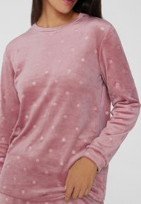 Hellrosa, plüschiger Sweatshirt mit erhobenem, kreisförmigem Punktmuster. Rundhalsausschnitt und lange Ärmel. Weiche Textur und lockere Passform.