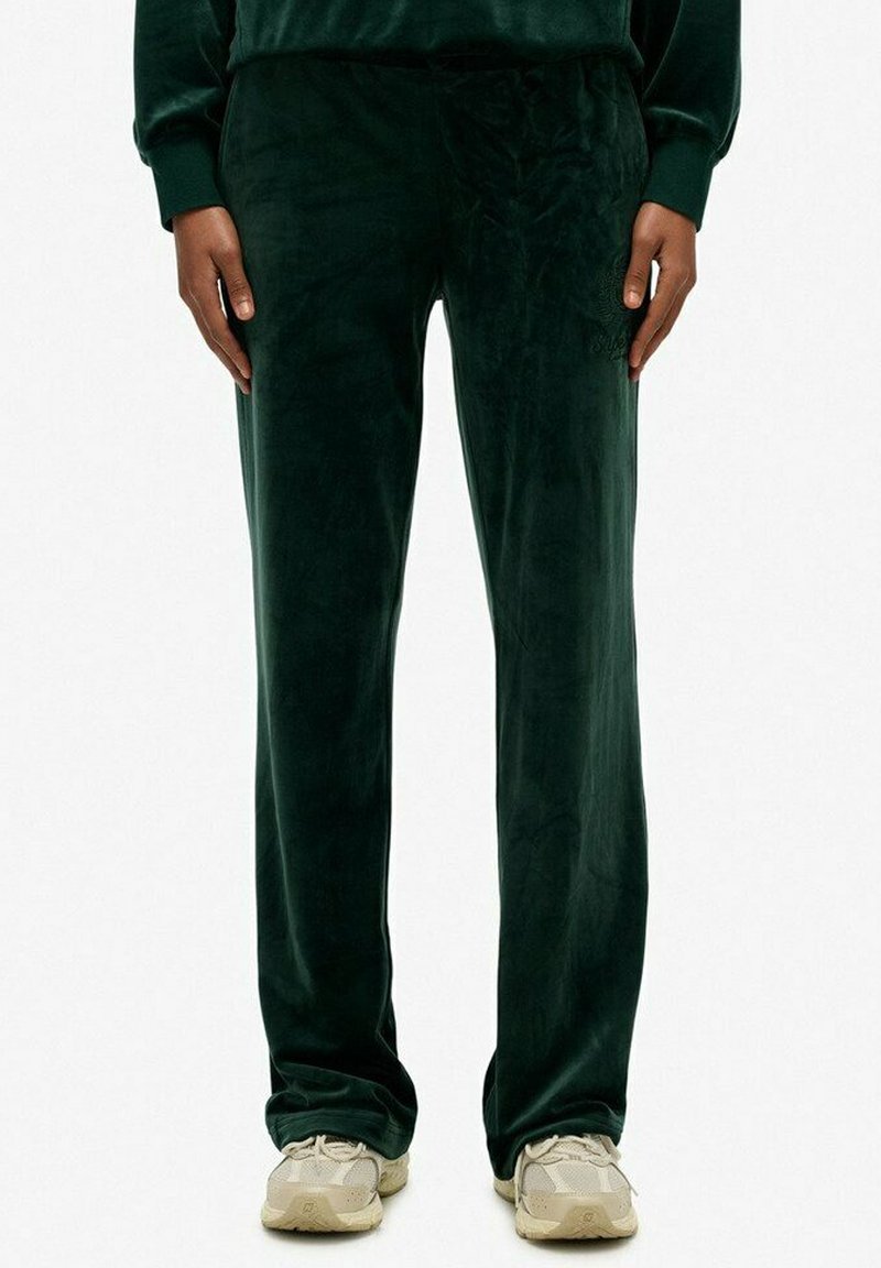 Donkergroene velours broek met een zachte textuur, voorzien van een relaxte pasvorm en subtiele geborduurde logodetails op de taille.