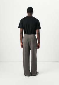 Black cotton T-shirt and gray wide-leg trousers with a textured finish. Trousers feature two back pockets and an elastic waistband.