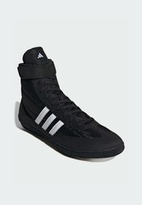 Černá vysoká sportovní bota s textilním a syntetickým svrškem, která má tři bílé pruhy, šněrování a polstrovaný kotník.