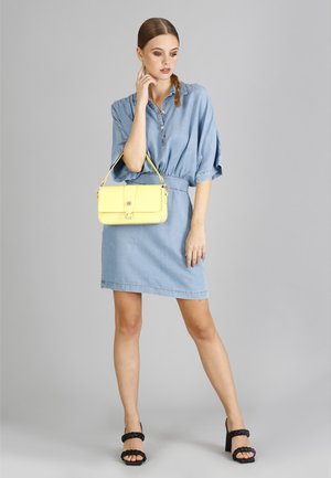 Denimkleid mit kurzen Ärmeln, Kragen und elastischem Bund. Gelbe Umhängetasche mit Verschluss und schwarze Sandalen mit Absatz und geflochtenen Trägern.