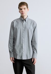 Szürke és fehér csíkos, hosszú ujjú ing gombos gallérral, karcsúsított szabással és puha pamut anyagból. Kis logó a mellrészen.