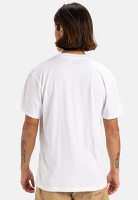 T-shirt bianco in cotone con collo rotondo, maniche corte e vestibilità rilassata. La vista posteriore mostra un design pulito senza stampe o loghi visibili.