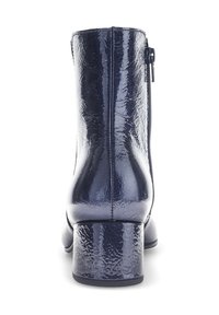Bottines en cuir bleu marine avec une finition texturée, talon bloc rectangulaire et fermeture éclair sur le côté. Surface lisse et réfléchissante avec un minimum de coutures.
