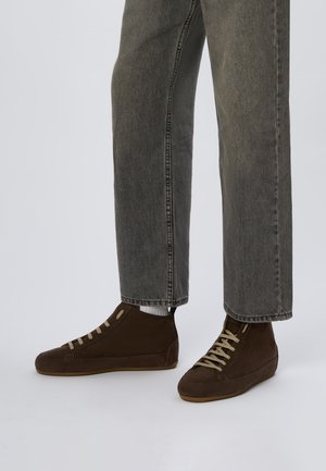 Sneakers alte in suede marrone con lacci beige chiaro. Sides texturizzati e suola in gomma, abbinati a jeans grigi a gamba dritta.