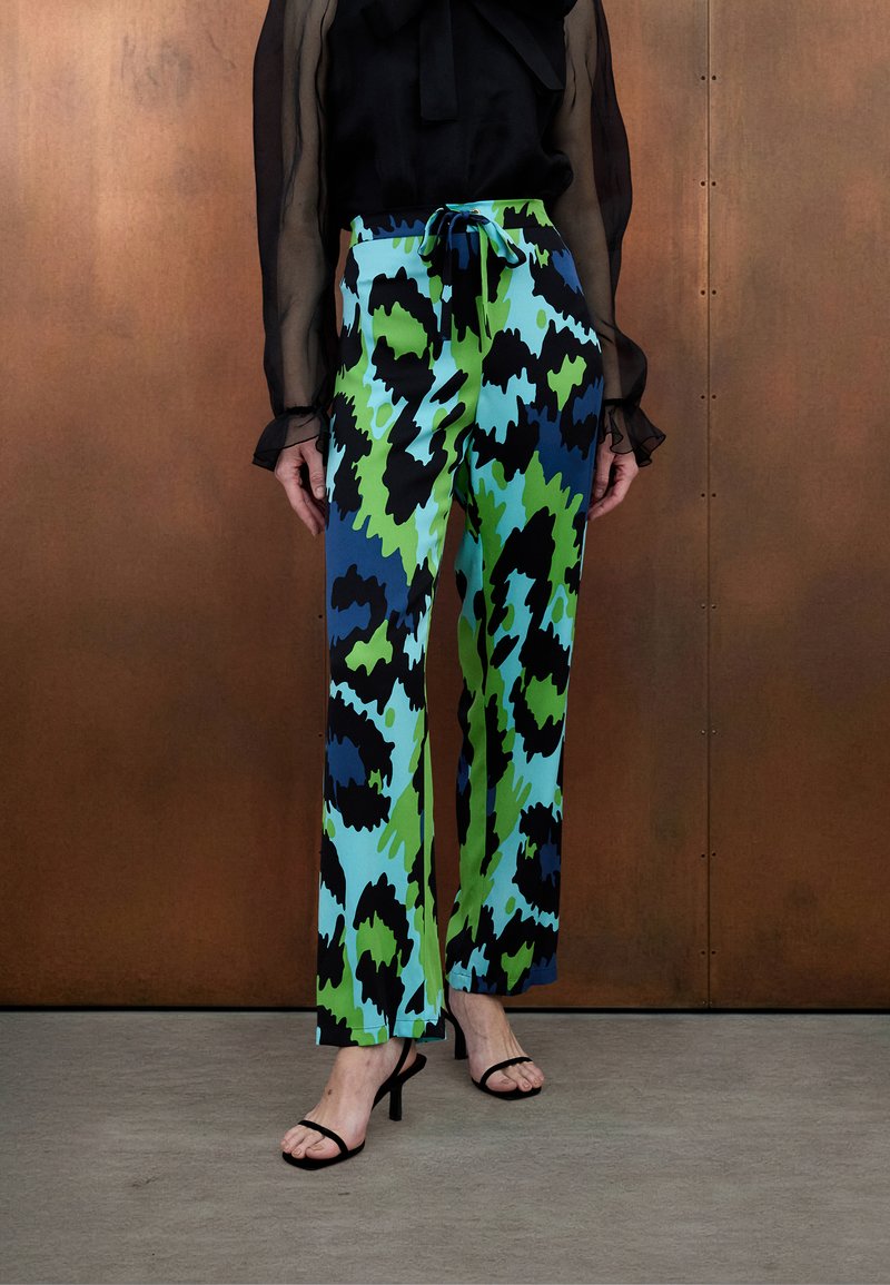 Bunte, weit geschnittene Hosen mit grünem, blauem und schwarzem abstraktem Muster, mit einem Kordelzugbund und glattem, leichtem Stoff.