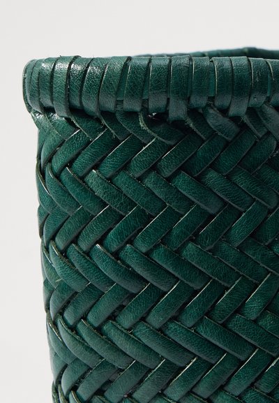 Panier en cuir vert tissé avec une surface texturée, arborant un design tressé et un bord supérieur lisse et enroulé.
