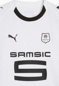 Camiseta deportiva blanca con acentos negros. Presenta el logo de Puma, 'SAM SIC' en texto negro en negrita y el emblema del Stade Rennais en el pecho. Patrón texturizado visible.