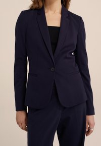 Marinblå blazer i smidigt tyg, med en knappstängning, slagkrage och två sidofickor; skräddarsydd passform, långa ärmar.