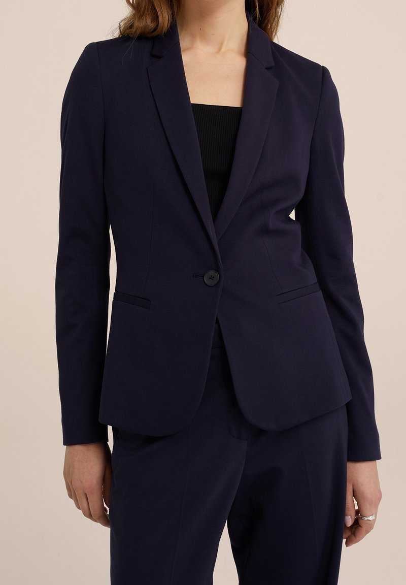 Marinblå blazer i smidigt tyg, med en knappstängning, slagkrage och två sidofickor; skräddarsydd passform, långa ärmar.