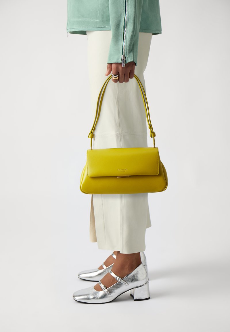 Yellow leather handbag with a rectangular shape and rounded edges, featuring a single short handle and a metallic clasp detail.