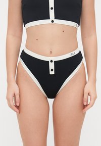 Svart teksturert bikini sett med en kort topp og høyt midje-bunn, begge med hvite detaljer og knapper, som viser en tett passform.