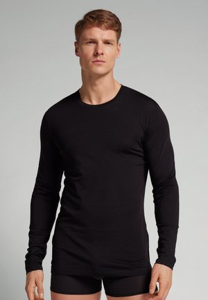 Zwarte longsleeve shirt gemaakt van zachte stof, met een ronde hals en een getailleerd ontwerp. Draag het over zwarte shorts, met een gladde textuur zonder patronen.