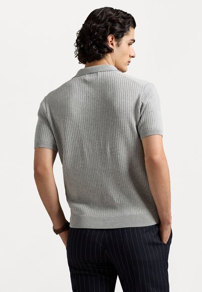 Grijze trui met korte mouwen en ribbels, voorzien van een platte kraag. Zachte textuur, rechte zoom, gecombineerd met donkergestreepte broek. Casueel ontwerp.
