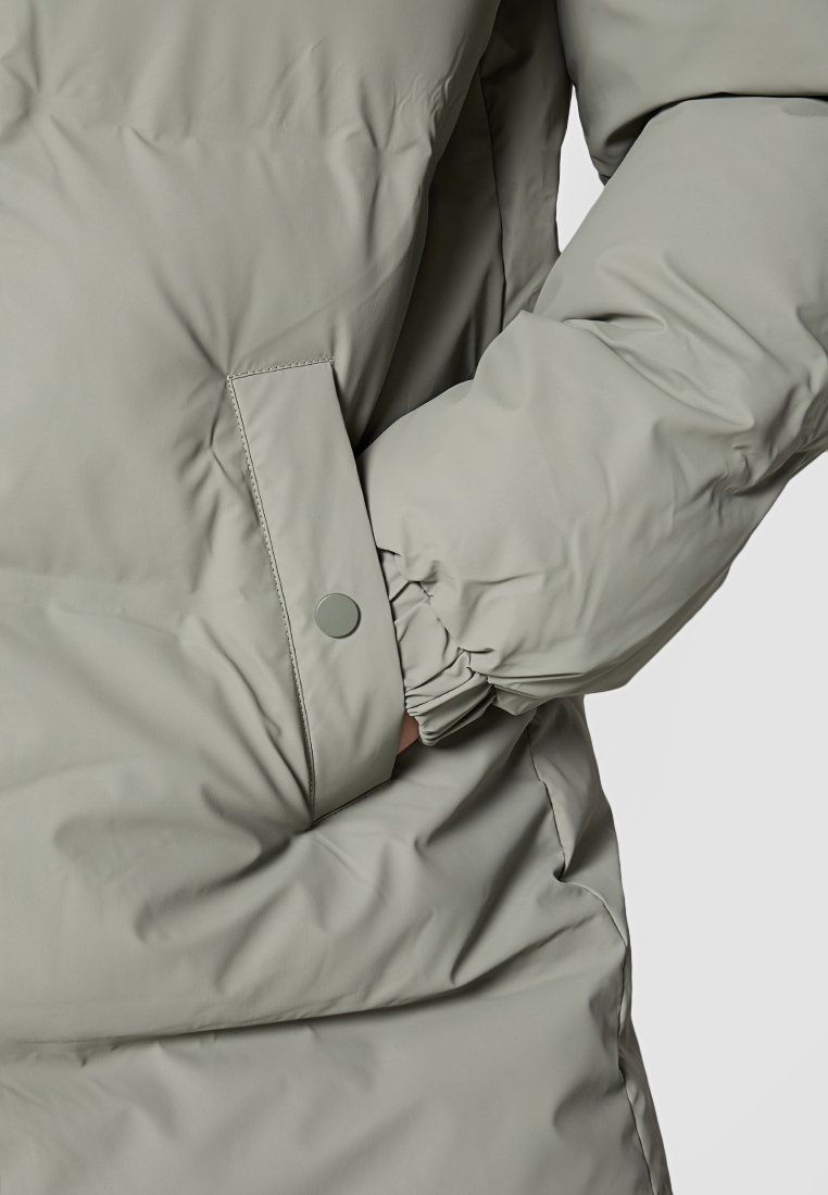 Hellgraue gepolsterte Jacke mit elastischen Bündchen, einer Druckknopf-Tasche und einer weichen, glatten Textur. Fokus auf Funktionalität und Wärme.