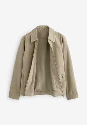 Beige színű cipzáras dzseki gallérral és két oldalsó cipzáras zsebbel, kinyitva, hogy felfedje a hozzá illő bézs bélését.