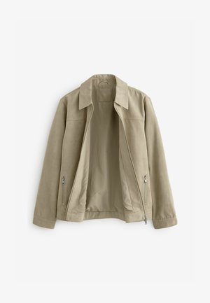 Beige színű cipzáras dzseki gallérral és két oldalsó cipzáras zsebbel, kinyitva, hogy felfedje a hozzá illő bézs bélését.