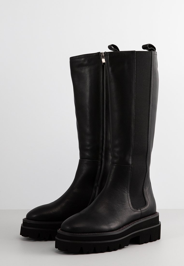 Hohe schwarze Lederstiefel mit robusten profilierten Sohlen, seitlichem Reißverschluss und elastischen Einsätzen für ein einfaches Anziehen.