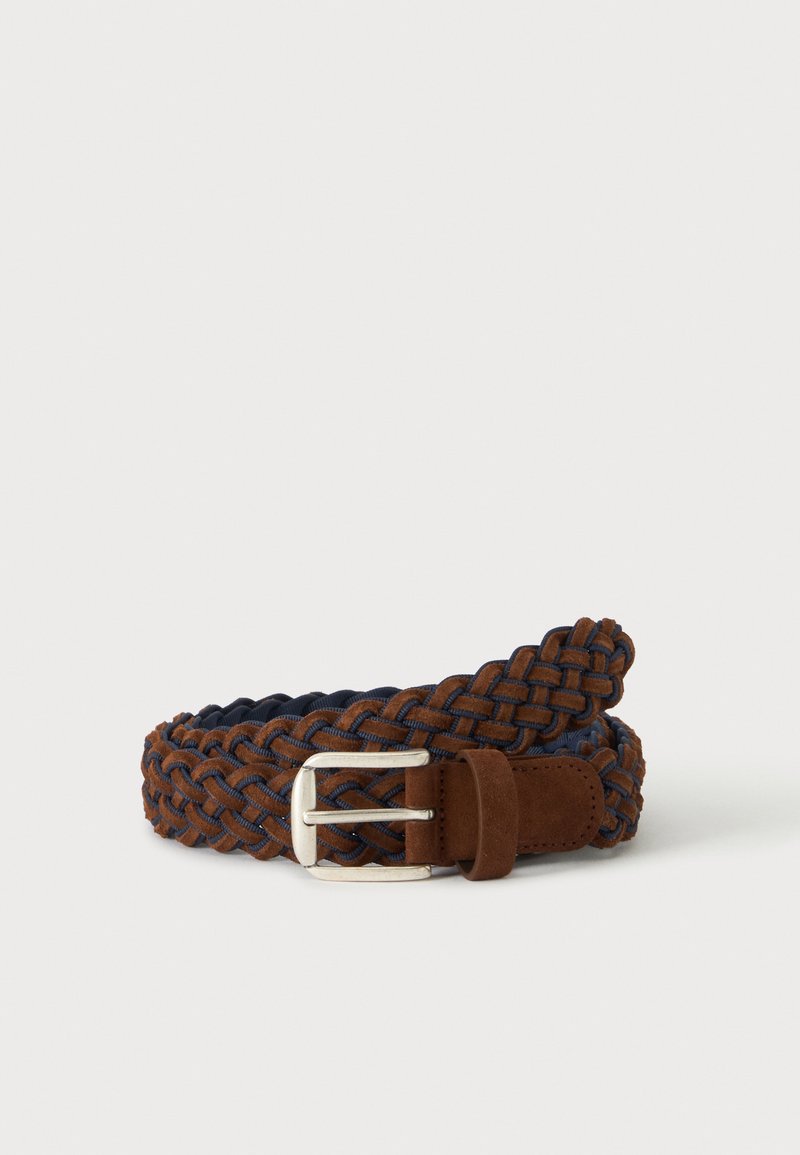 Ceinture en cuir tressé marron avec boucle rectangulaire argentée et passant en suède à l’extrémité sur fond blanc.