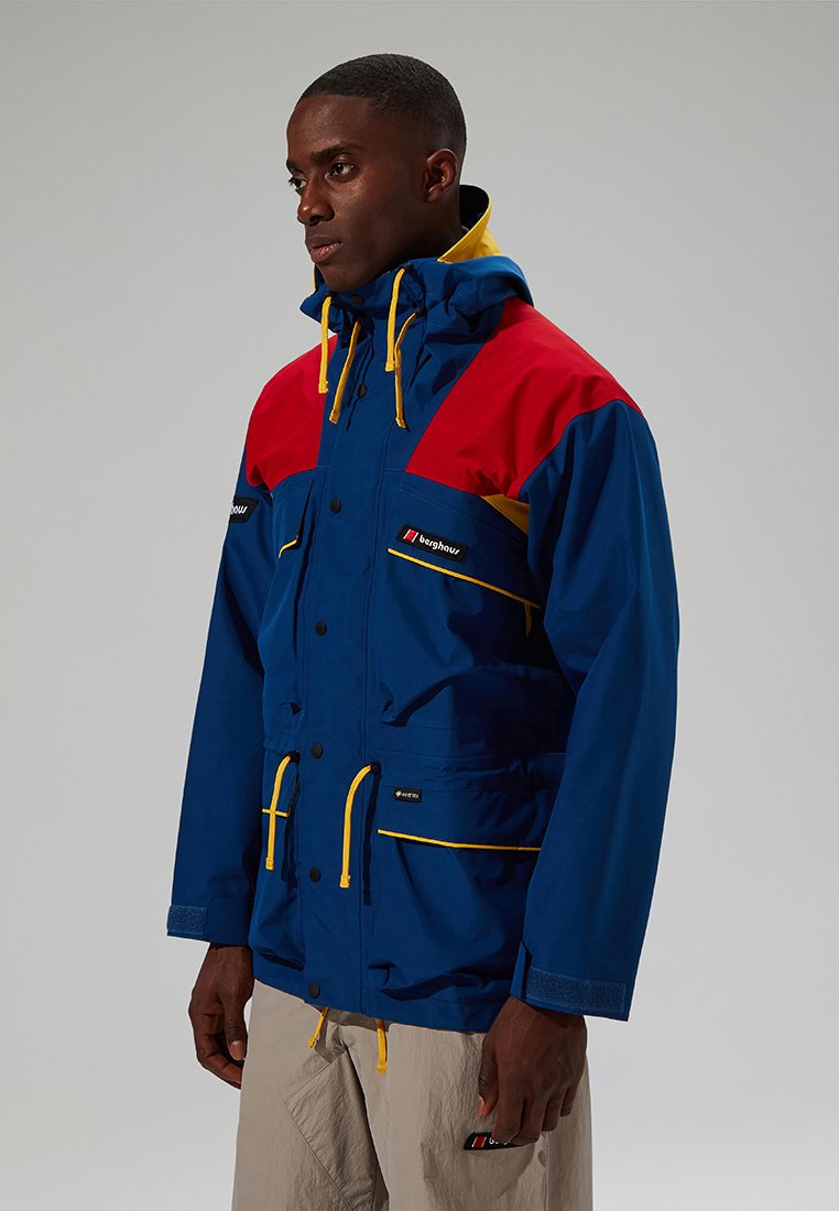Blauere wasserdichte Jacke mit roten und gelben Akzenten, ausgestattet mit einer Kapuze, Reißverschlusstaschen und verstellbaren Kordeln.