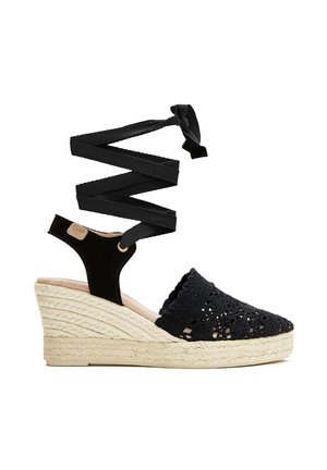 Alpargata negra tejida con cuña, puntera cerrada, cintas para atar en el tobillo y plataforma con tacón de yute trenzado.