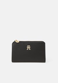 Black leather wallet with a smooth texture, featuring a gold-tone logo on the front and a zip closure along the top edge.