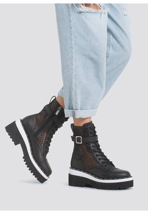 Stivaletti neri alla caviglia con design a rete, chiusura con lacci, dettaglio con fibbia e suola platform bianca con grip testurizzato. Indossati con jeans chiari strappati.